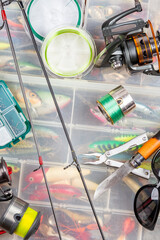 Different fishing tacles with lures and reels on wooden brown background with place for text.