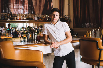 Fototapeta na wymiar Young man standing at bar while waiting for meeting