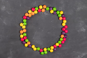 Round frame of multi-colored round candies on a gray background for inscriptions