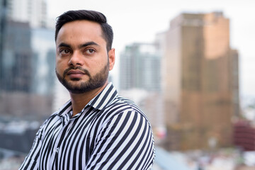 Young bearded Indian businessman against view of the city