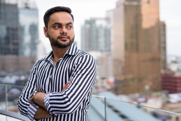 Obraz premium Young bearded Indian businessman against view of the city