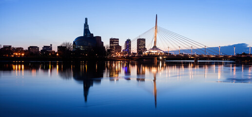 Illuminated skyline reflecting in calm Assiniboine River