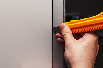 a hand opening the panel with a knife with a retractable blade