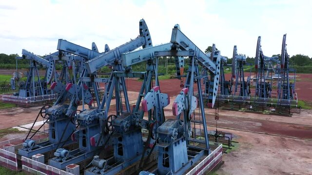 Working Pumpjack industrial oil pump jack working and pumping crude oil for fossil fuel energy with drilling rig 
