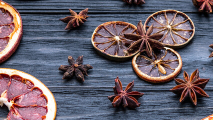 Dried citrus fruits, orange, lime, grapefruit, anise. Dark natural wooden background. Autumn theme layout.