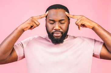 Stressed young african american man feel pain having terrible strong headache concept, tired upset black guy massaging temples suffering from migraine isolated on pink studio background.