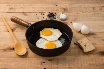 fried eggs, in a frying pan, on wooden background.
