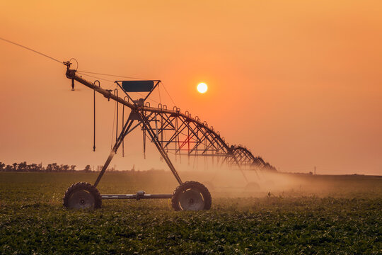 Silhouette of irrigation system with sun setting in the background