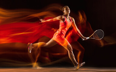 Fire flame. Professional female tennis player training isolated on black studio background in mixed light. Woman in sportsuit practicing. Healthy lifestyle, sport, workout, motion and action concept.