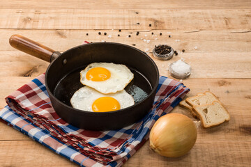 fried eggs, in a frying pan, on wooden background.