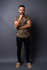 Young bearded Indian man against gray background