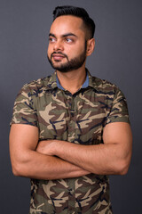 Young bearded Indian man against gray background