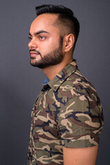 Young bearded Indian man against gray background