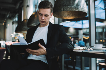 Serious businessman reading book in cafe
