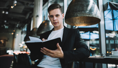 Determined businessman writing in notebook during remote work in cafe