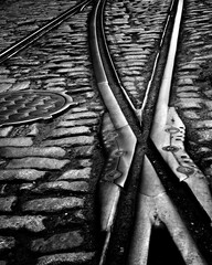 Vintage iron train tracks and manhole covers contrast with granite paving 1