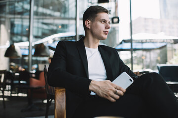 Fototapeta premium Serious businessman with smartphone in cafe