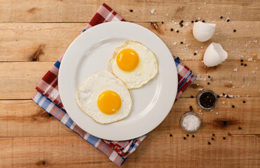 fried eggs, on a white plate, on wooden background. Top Wiew