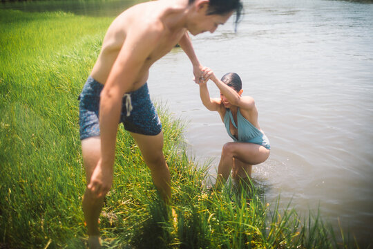 Young man helps young woman out of mucky water