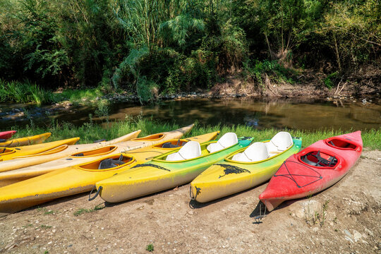 A set of ten old and worn kayak of various color.