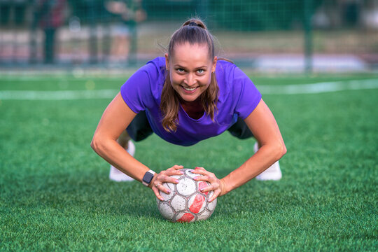 Young woman doing push ups using a ball
