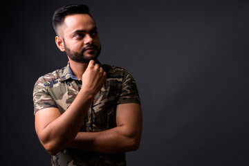 Young bearded Indian man against gray background