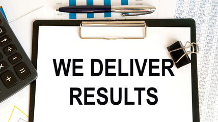 Business concept. Notebook with text WE DELIVER RESULTS sheet of white paper for notes, glasses in the white background