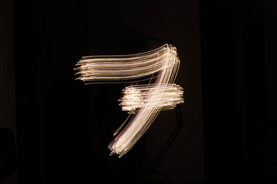 Foto de larga exposici&oacute;n de senderos de luz haciendo una forma de n&uacute;meros sobre un fondo negro  con luces led para texto