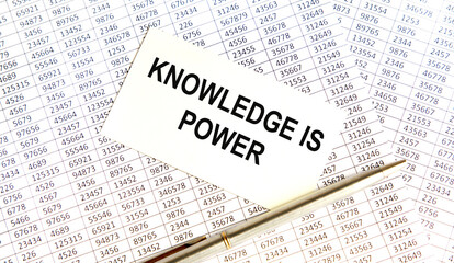 Text KNOWLEDGE IS POWER on the page of a notepad lying on financial charts on the office desk. Near the calculator and marker. Business concept.