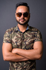 Young bearded Indian man against gray background