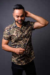 Young bearded Indian man against gray background