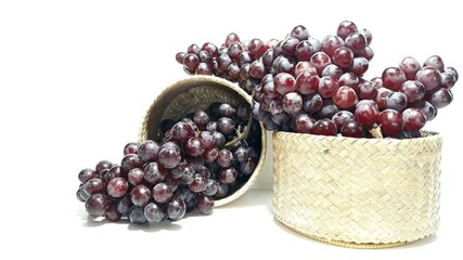 A bunch of grapes in a wooden box made of woven bamboo.