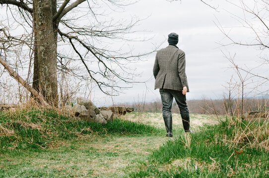 Back of man walking through woods, from behind