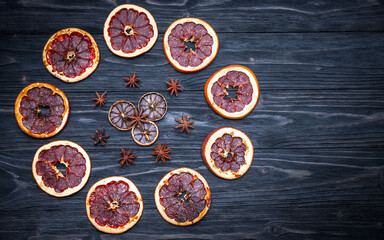 Obraz na płótnie Canvas Dried citrus fruits, orange, lime, lemon, grapefruit, anise. Dark natural wooden background. Flat lay, top view, copy space. Autumn decoration theme layout. 