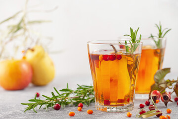 Winter or autumn hot healing tea with pear, orange, lingonberries, sea buckthorn and spices in glass cup.