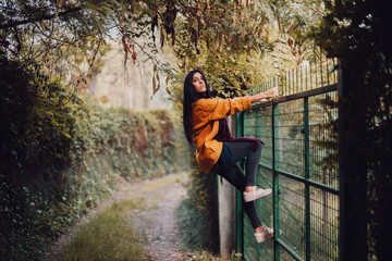 Woman looking through the metal fence in the forest