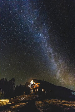 alpine cabin in the mountains at night with the milky way above