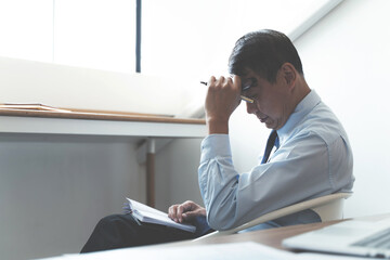 Stressed mature businessman suffering headache at office.