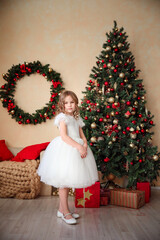 little beautiful girl in a white fluffy, elegant dress on the background of Christmas trees in the interior of the loft. new year holidays and vacations.