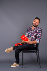 Young bearded Indian man against gray background