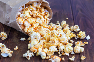 A transparent bowl of popcorn on a wooden surface. Next to a laptop and headphones. The mask protects against viruses.