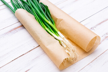 A bunch of green onions on a light wooden background.