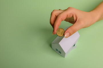 White family paper house in man hand on mint background paper. Minimalistic and simple concept, style. Copy space. Horizontal orientation.