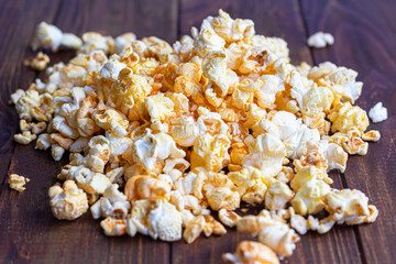 A transparent bowl of popcorn on a wooden surface. Next to a laptop and headphones. The mask protects against viruses.