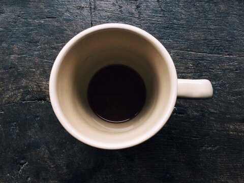 Overhead view of an empty cup of coffee on a wooden table