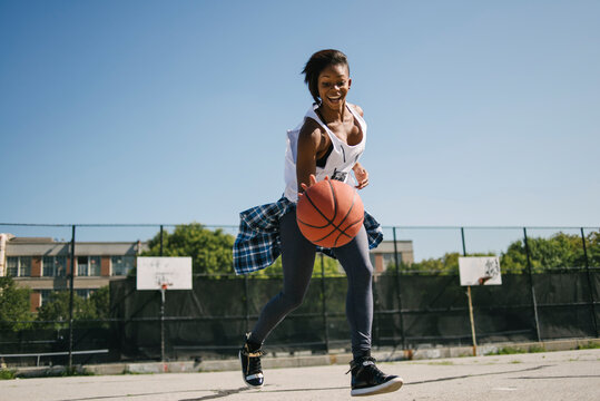 Young woman playing basketball outdoors in urban area