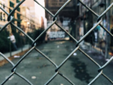 Cityscape and graffiti seen through a chain linked fence