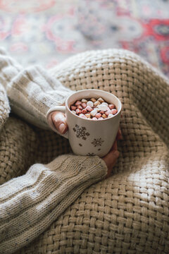 Woman covered with warm blanket holding a cup of cocoa