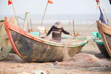 Fishermen repairing nets on a boat trip out to sea in the afternoon July 31, 2016 at the beach of Hai Ly, Vietnam.