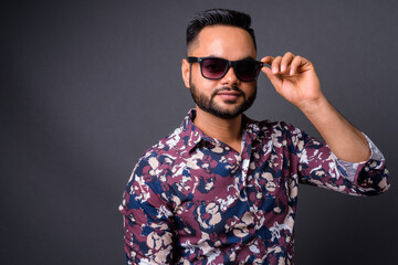 Young bearded Indian man against gray background